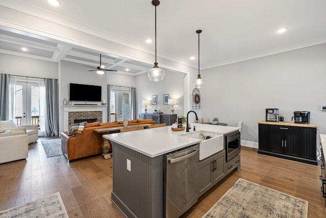 kitchen featuring a sink, open floor plan, a kitchen island with sink, light countertops, and appliances with stainless steel finishes