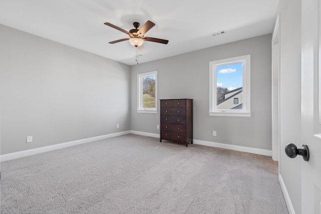 unfurnished bedroom featuring baseboards, visible vents, light colored carpet, and ceiling fan