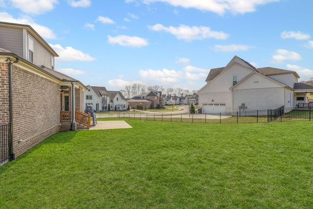 view of yard with a residential view, a fenced backyard, and a garage