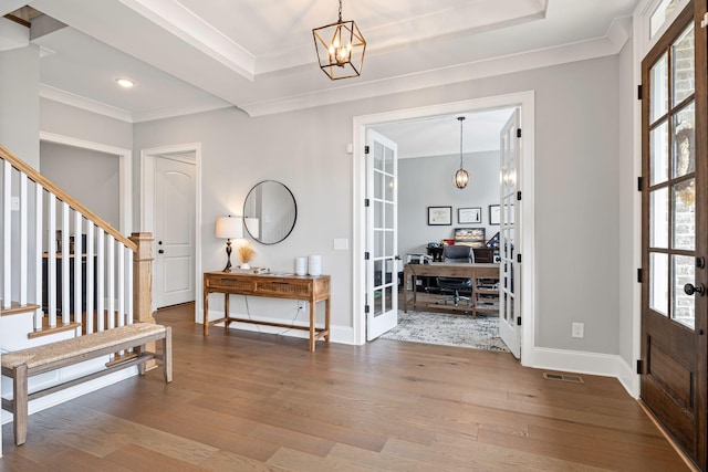 foyer with a raised ceiling, french doors, plenty of natural light, and wood finished floors