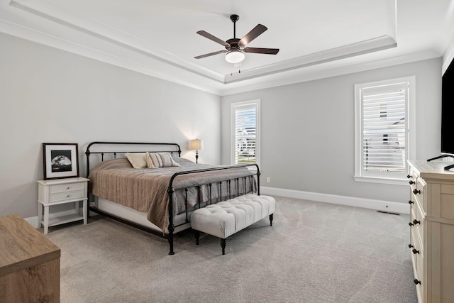 bedroom featuring crown molding, baseboards, light carpet, and a raised ceiling