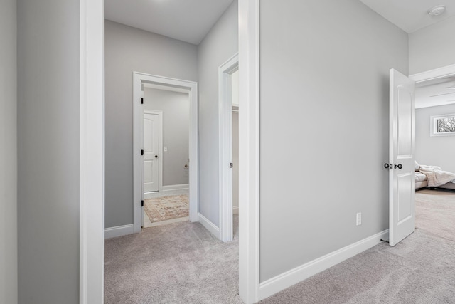 hallway with baseboards and light carpet