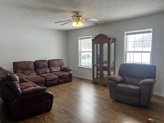 living area featuring a wealth of natural light, a ceiling fan, dark wood-style floors, and a textured ceiling