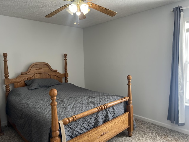 carpeted bedroom featuring baseboards, multiple windows, ceiling fan, and a textured ceiling