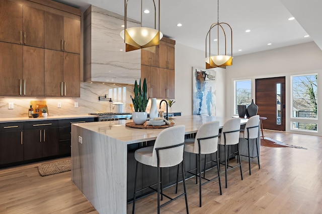 304 35th Ave N, Nashville, TN 37209 - kitchen featuring a kitchen island with sink, tasteful backsplash, a kitchen bar, pendant lighting, and light wood finished floors