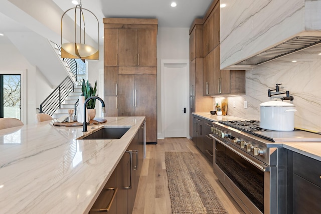 304 35th Ave N, Nashville, TN 37209 - kitchen featuring premium range hood, stainless steel stove, a sink, light stone counters, and pendant lighting