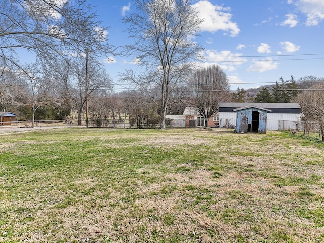 view of yard featuring a shed, fence, and an outbuilding