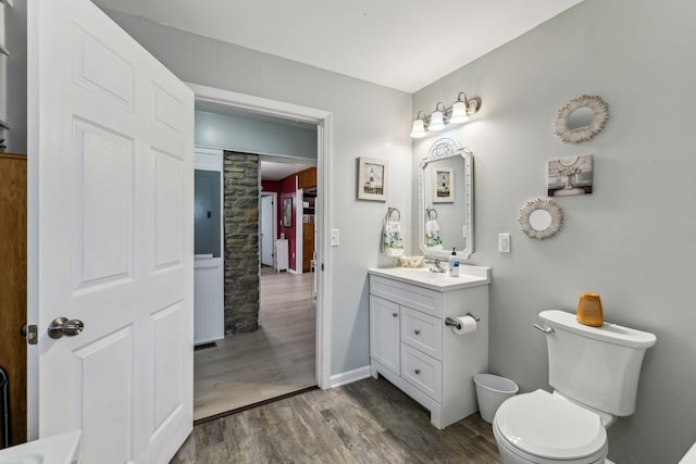 bathroom featuring baseboards, vanity, toilet, and wood finished floors