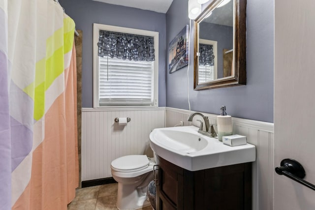 full bath featuring vanity, toilet, wainscoting, and tile patterned floors