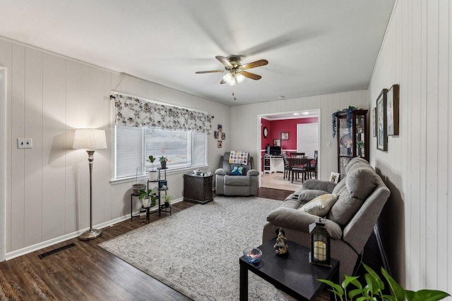 living area featuring ceiling fan, visible vents, dark wood-style floors, and baseboards