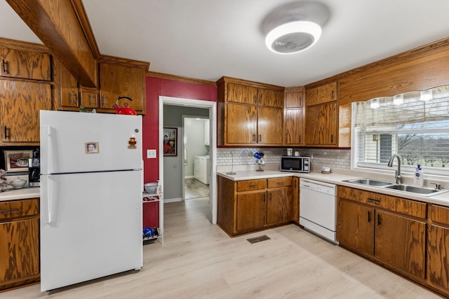 kitchen with light countertops, visible vents, a sink, white appliances, and brown cabinetry