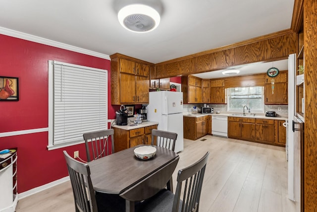 dining area with baseboards, ornamental molding, and light wood-type flooring