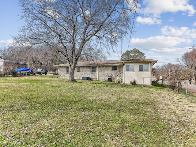 back of property featuring fence, cooling unit, and a yard