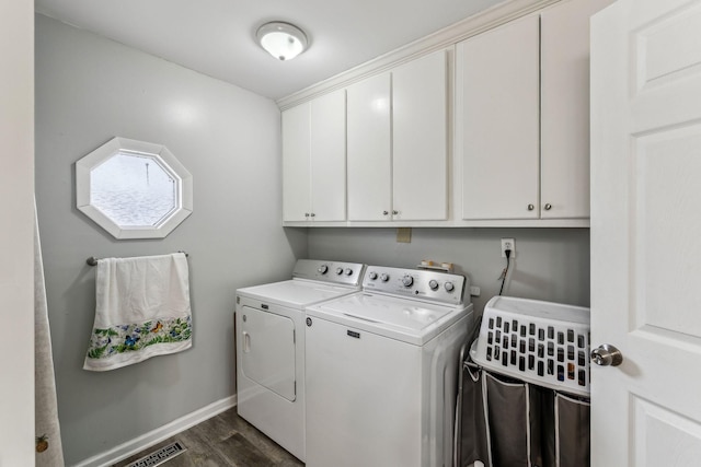 clothes washing area with baseboards, washing machine and dryer, visible vents, dark wood-type flooring, and cabinet space