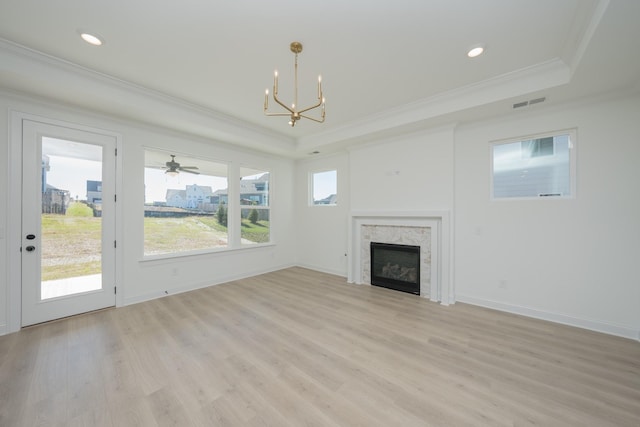 unfurnished living room with ornamental molding, light wood-type flooring, a raised ceiling, and a high end fireplace