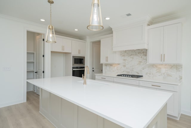 kitchen featuring a sink, hanging light fixtures, black oven, a large island with sink, and light countertops