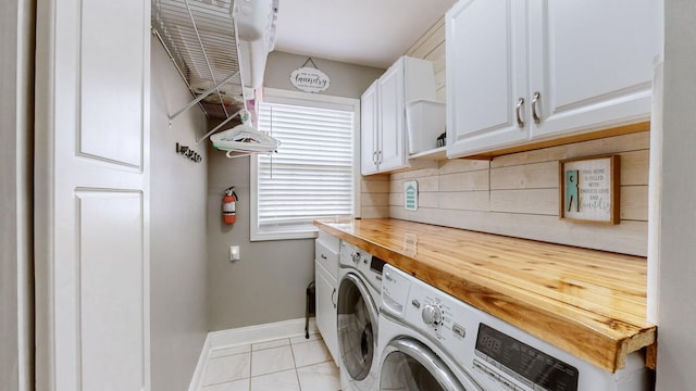 laundry area with baseboards, cabinet space, light tile patterned flooring, and washer and dryer