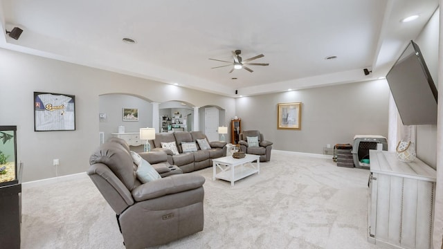 living room featuring arched walkways, decorative columns, light carpet, and baseboards