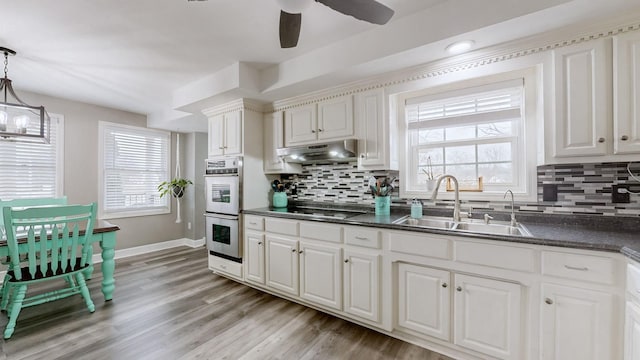 kitchen featuring a sink, double oven, pendant lighting, and white cabinets