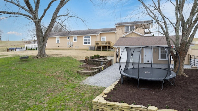 rear view of property featuring a lawn, cooling unit, a trampoline, a vegetable garden, and driveway