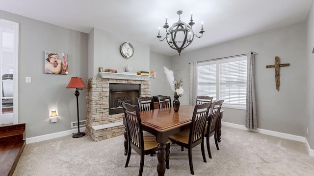 carpeted dining room featuring a notable chandelier, visible vents, baseboards, and a stone fireplace