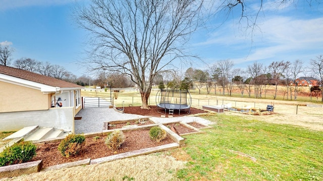 view of yard with fence, a trampoline, and a vegetable garden