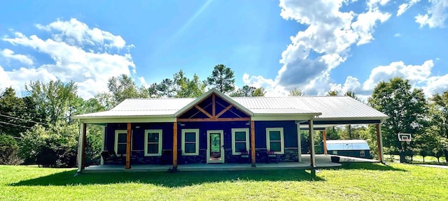 rear view of house with metal roof, a lawn, and covered porch