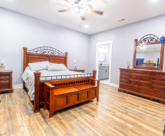 bedroom featuring ensuite bath, baseboards, visible vents, and light wood-style floors