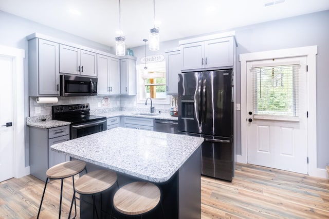 kitchen with a sink, a kitchen island, hanging light fixtures, stainless steel appliances, and backsplash