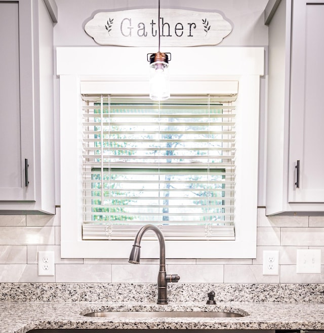 interior details featuring light stone counters, tasteful backsplash, and a sink