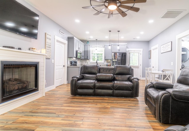 living room featuring a fireplace, visible vents, baseboards, and light wood-style floors