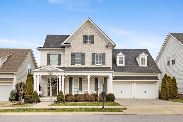 traditional-style house with brick siding, a porch, concrete driveway, and roof with shingles