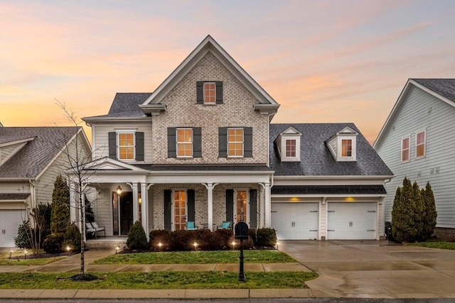 traditional home with driveway, roof with shingles, an attached garage, covered porch, and brick siding