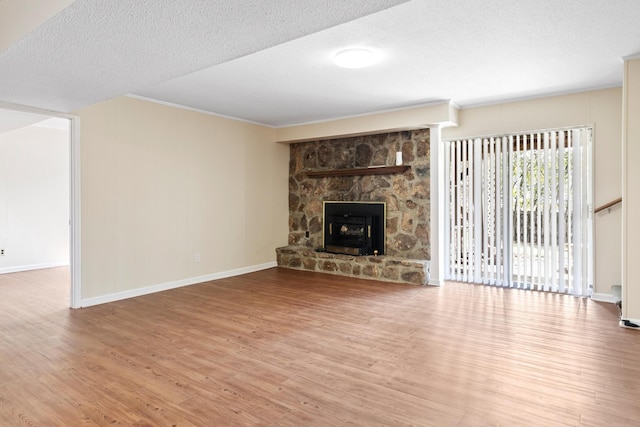 unfurnished living room with a textured ceiling, baseboards, a fireplace, and wood finished floors