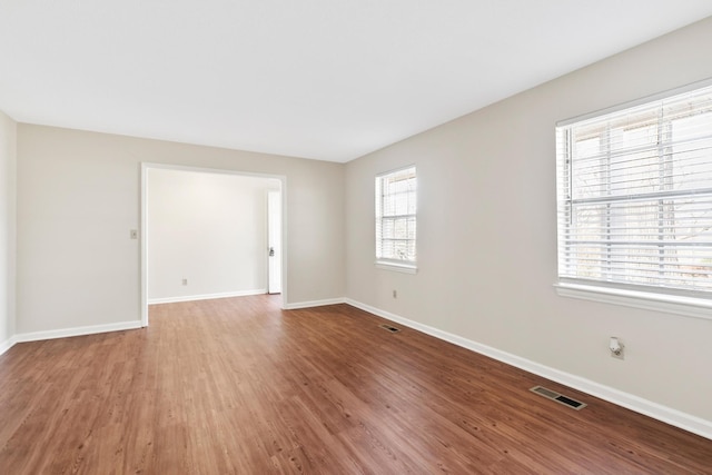 spare room with baseboards, visible vents, and wood finished floors