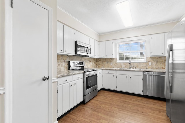 kitchen with white cabinetry, appliances with stainless steel finishes, light countertops, and a sink