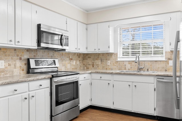 kitchen featuring a sink, crown molding, light countertops, appliances with stainless steel finishes, and white cabinets