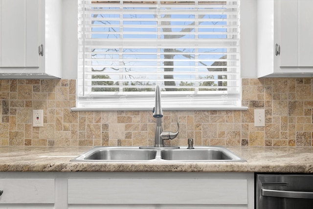 interior details featuring decorative backsplash, white cabinetry, light countertops, and a sink