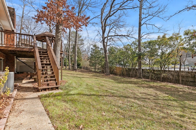 view of yard with central AC, a fenced backyard, a wooden deck, and stairway