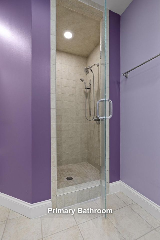 bathroom with baseboards, a stall shower, and tile patterned flooring