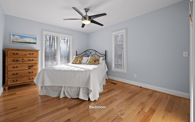 bedroom with baseboards, visible vents, a ceiling fan, and light wood-style flooring