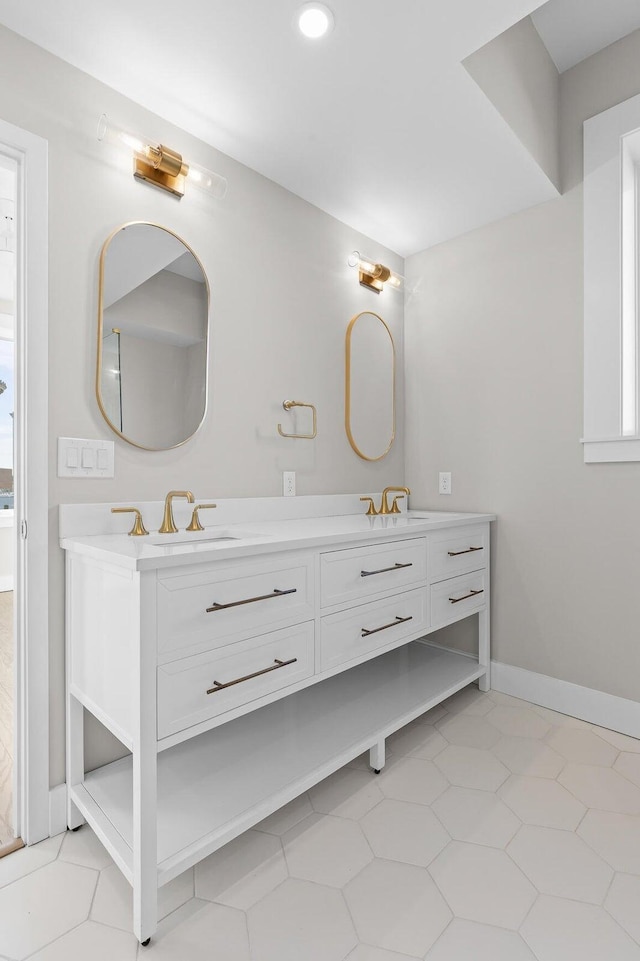 bathroom with double vanity, a sink, and baseboards