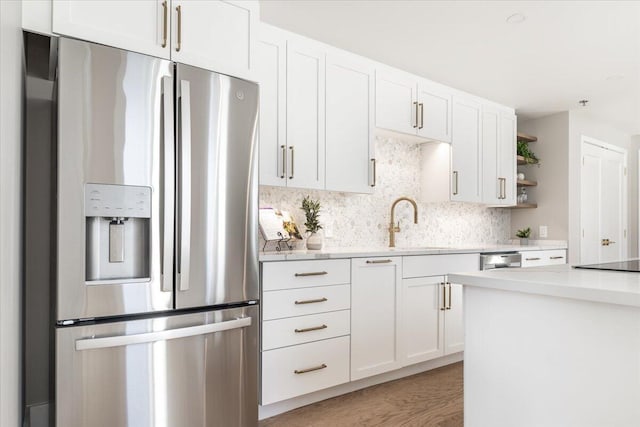 kitchen featuring a sink, white cabinetry, stainless steel refrigerator with ice dispenser, backsplash, and open shelves