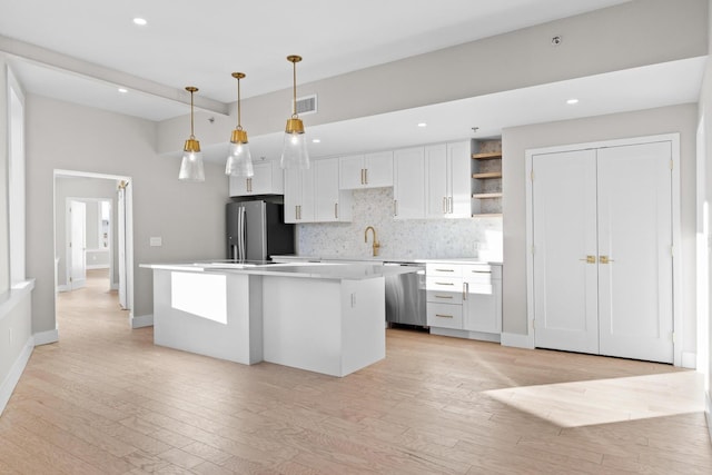 kitchen with stainless steel appliances, white cabinets, light countertops, open shelves, and pendant lighting