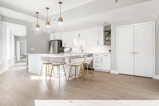 kitchen with stainless steel appliances, white cabinetry, light countertops, open shelves, and decorative light fixtures