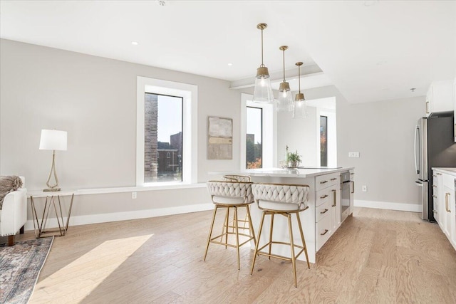 kitchen featuring stainless steel appliances, a kitchen island, white cabinetry, light countertops, and hanging light fixtures