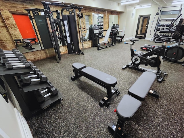 gym featuring brick wall and baseboards