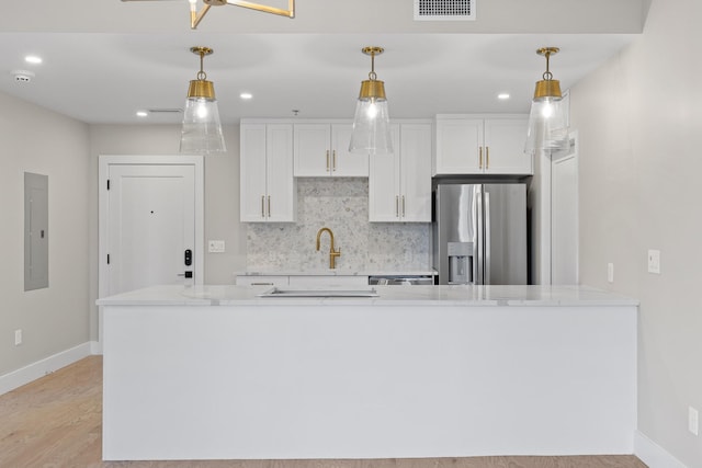 kitchen featuring visible vents, white cabinetry, backsplash, light stone countertops, and stainless steel fridge