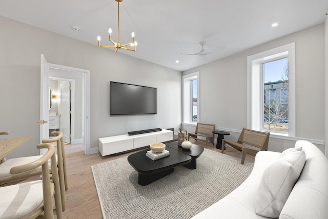 living area with light wood-style floors, ceiling fan with notable chandelier, baseboards, and recessed lighting