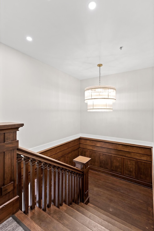 stairway with a wainscoted wall, wooden walls, wood finished floors, and recessed lighting